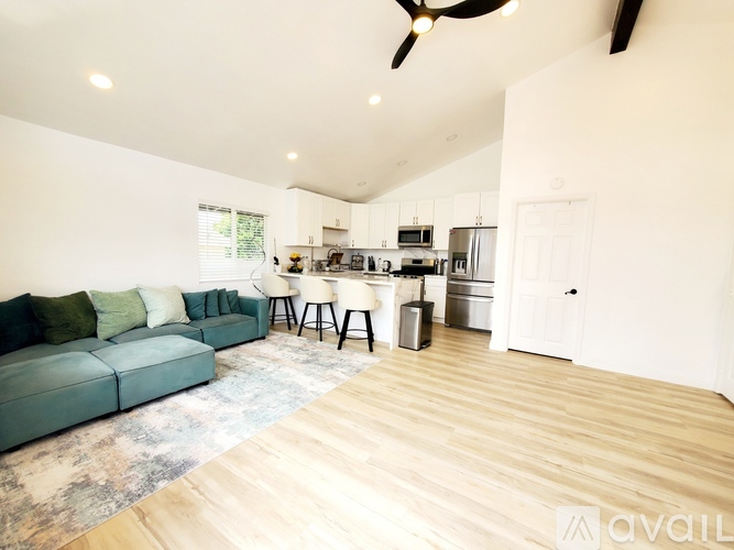 A living room with a green couch and a kitchen in the background.