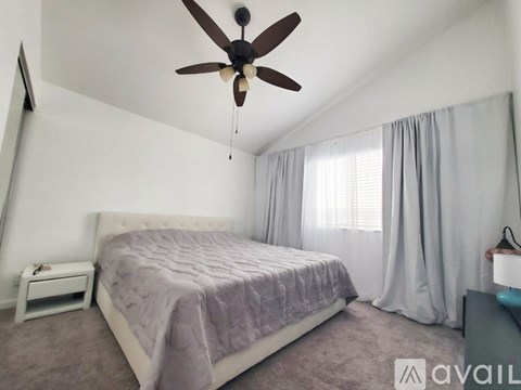 A bedroom with a bed, a ceiling fan, and a nightstand.