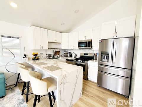 A kitchen with a white table and chairs, a stove, and a refrigerator.