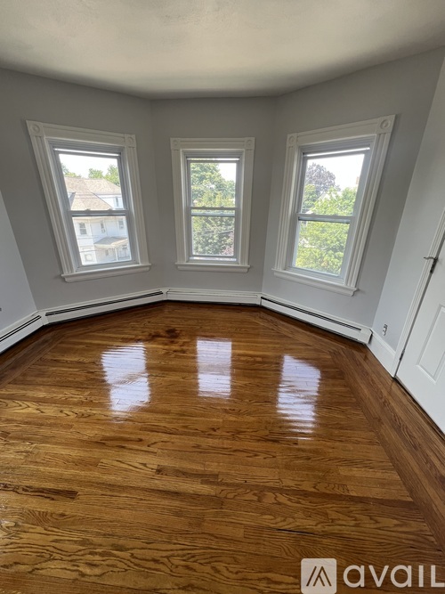 A room with wooden floors and three windows.
