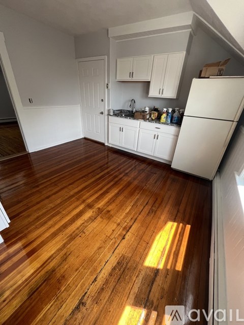 A kitchen with white cabinets and a wooden floor.