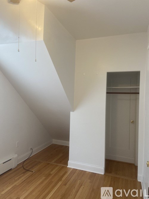 A room with wooden flooring and white walls.