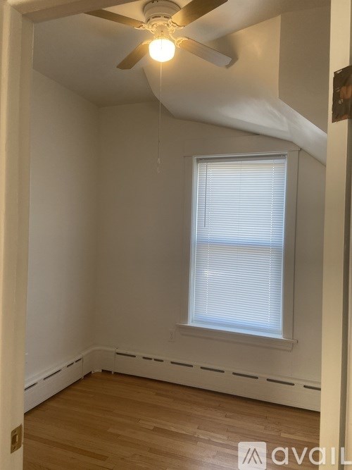 A room with a ceiling fan and a window with blinds.