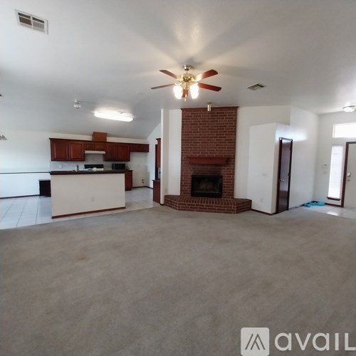 A living room with a fireplace and a kitchen in the background.