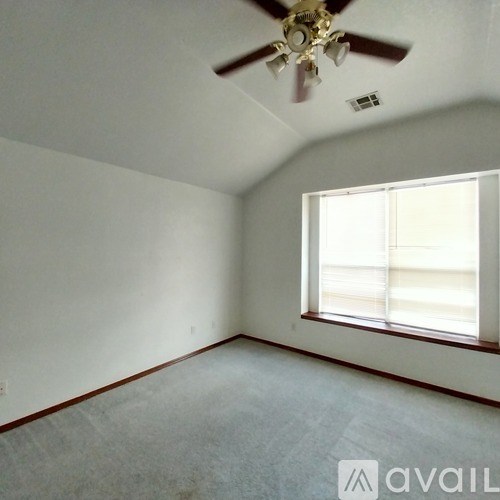A room with a ceiling fan and a window letting in light.