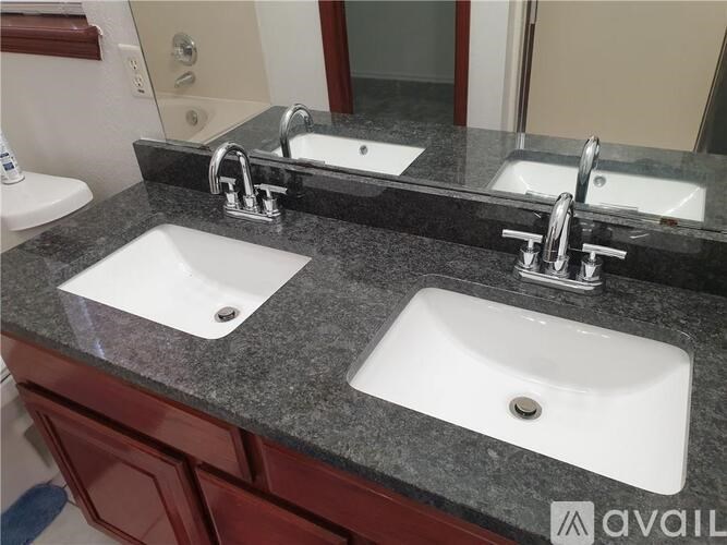 A bathroom counter with two sinks and a mirror.