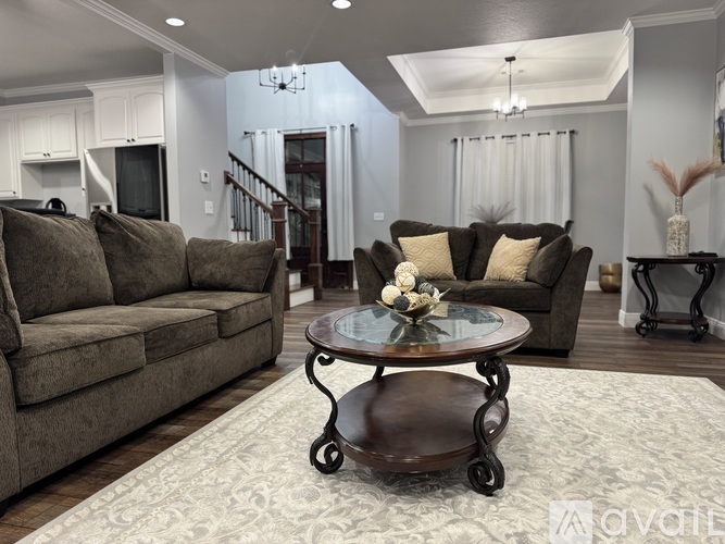 A living room with a brown couch, a round table, and a ceiling fan.
