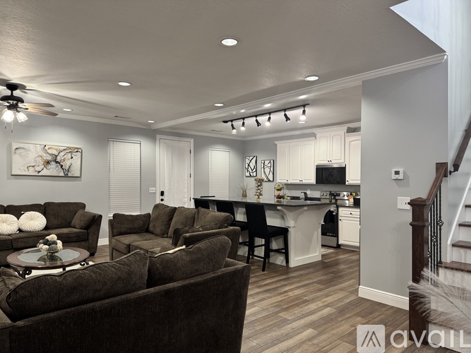 A living room with brown couches and a white kitchen in the background.
