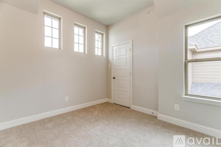 A room with a carpeted floor, a door, and three windows.
