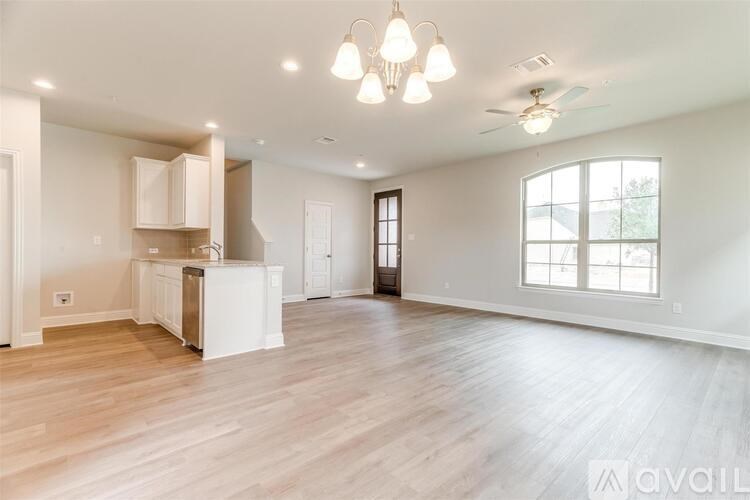A spacious living room with wooden flooring and a ceiling fan.
