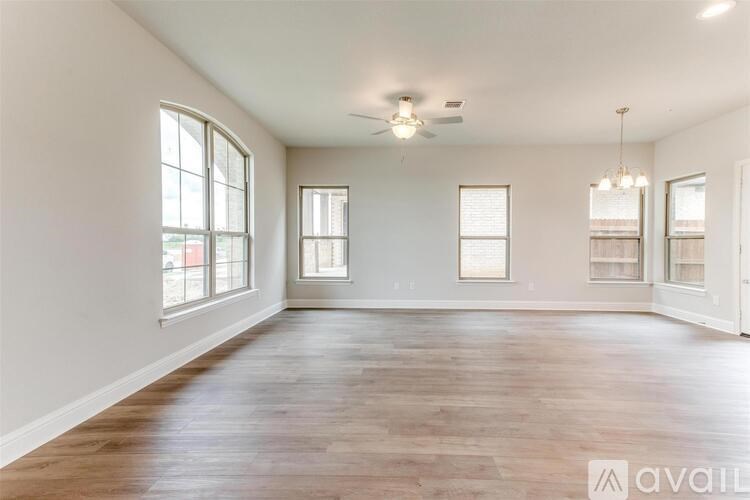 A spacious room with wooden floors and large windows.