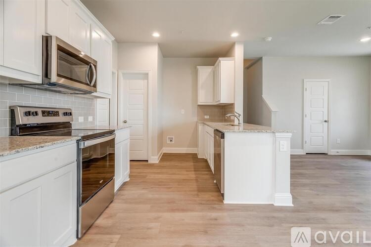 A kitchen with white cabinets and a wooden floor.