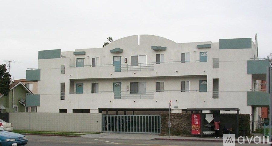 A white building with green trim and a blue car parked in front.