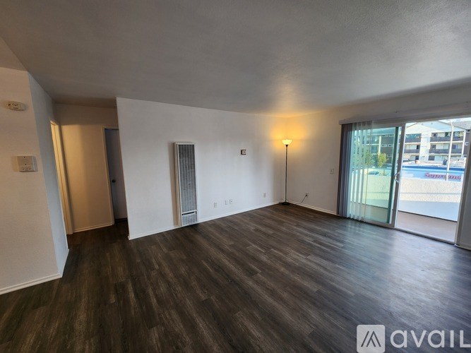 A spacious room with wooden flooring and a large window.