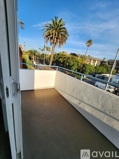 A balcony with a view of palm trees and a parking lot.