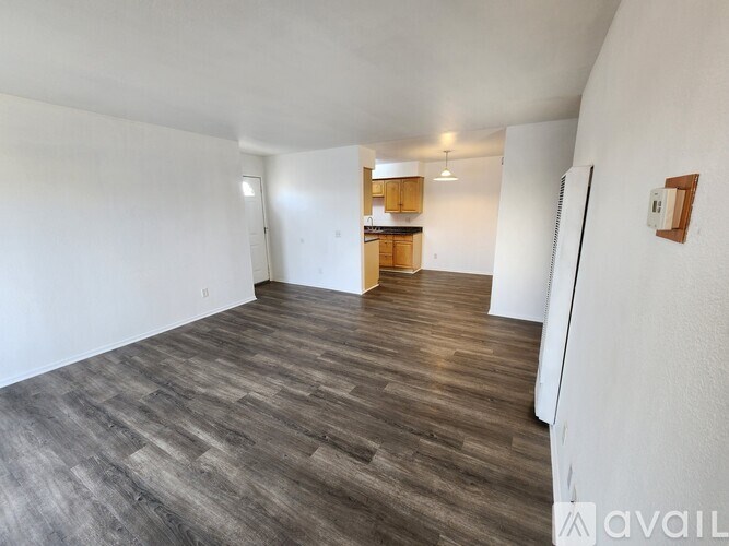 A spacious room with wooden flooring and white walls.