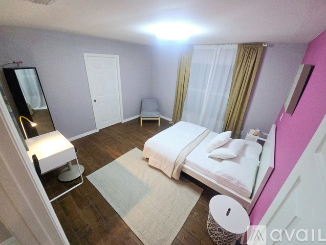 A bedroom with a bed, chair, and mirror.