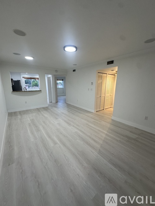 A spacious room with wooden flooring and white walls.