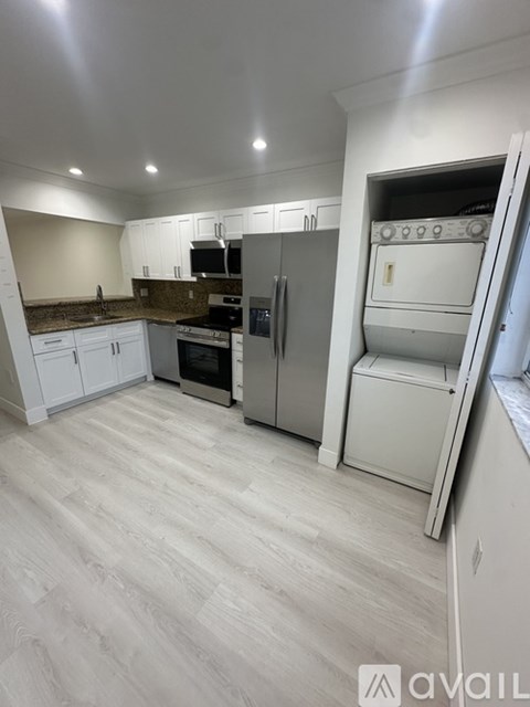 A kitchen with white cabinets and a refrigerator.