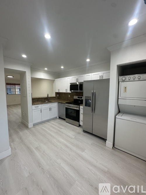 A kitchen with white cabinets and a refrigerator.