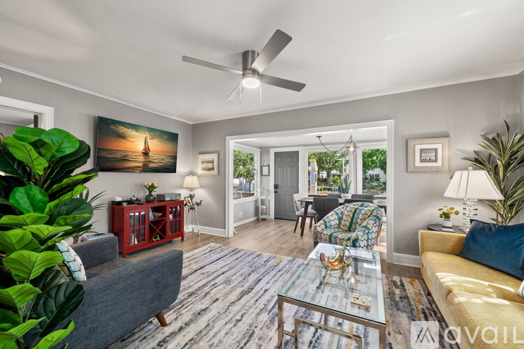 A living room with a grey couch, a red side table, and a ceiling fan.