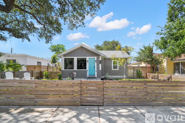 A house with a blue door is surrounded by a wooden fence.