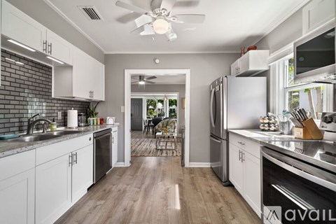A modern kitchen with white cabinets and stainless steel appliances.
