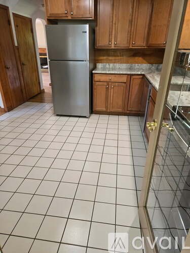 A kitchen with a refrigerator and wooden cabinets.