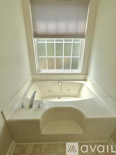 A white bathtub with a window above it.