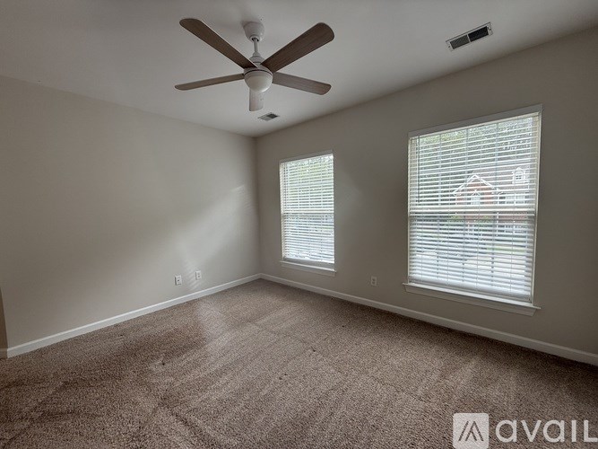 A room with a ceiling fan and two windows with blinds.