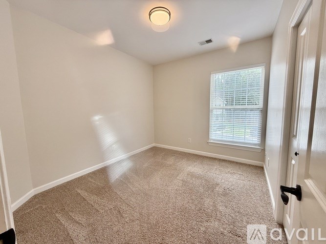 A carpeted room with a door and a window.