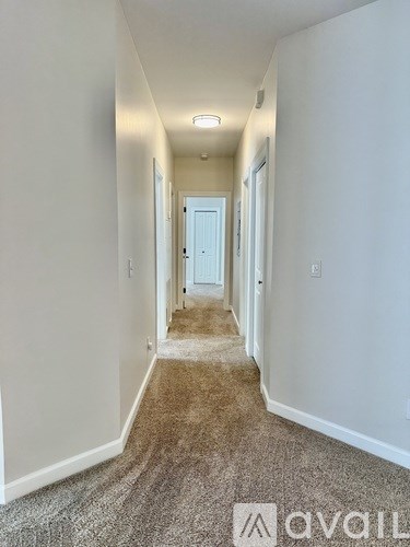 A long hallway with a carpeted floor and white walls.