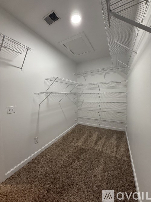 A room with a carpeted floor and a wall-mounted shelving unit.