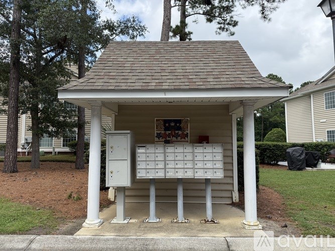 A small white pavilion with a brown roof is situated in a grassy area.