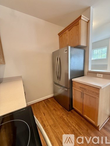 A kitchen with a black stove top and a silver refrigerator.