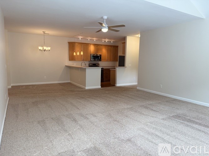 A living room with a carpeted floor and a ceiling fan.