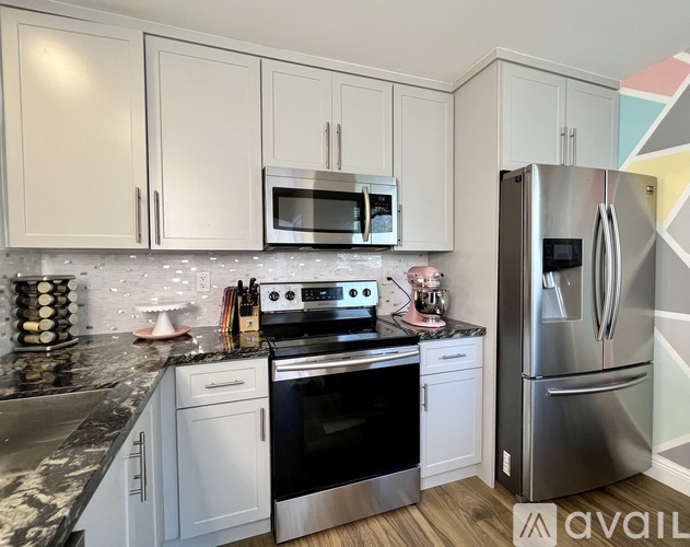 A kitchen with white cabinets and a black countertop.