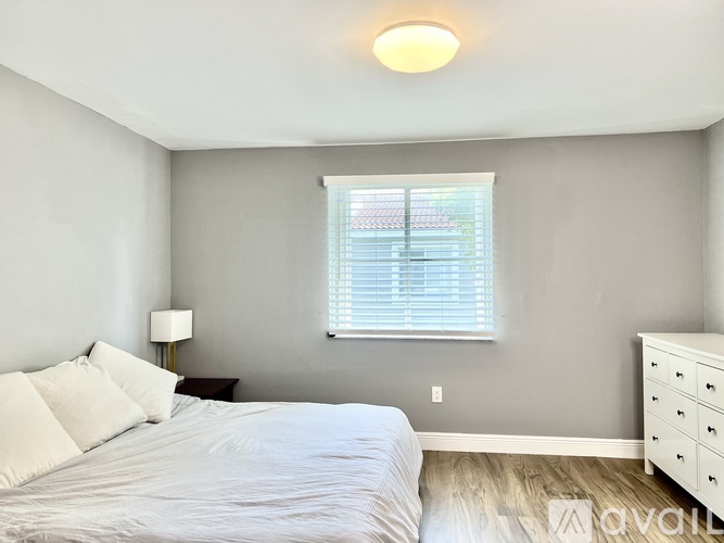 A bedroom with a bed, nightstand, and window.