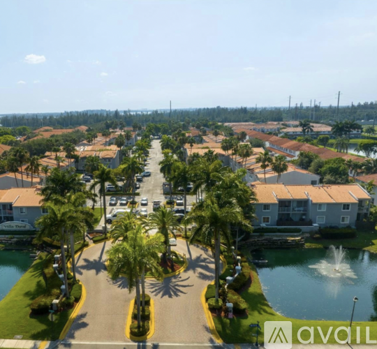 A view of a residential area with houses, palm trees, and a fountain.