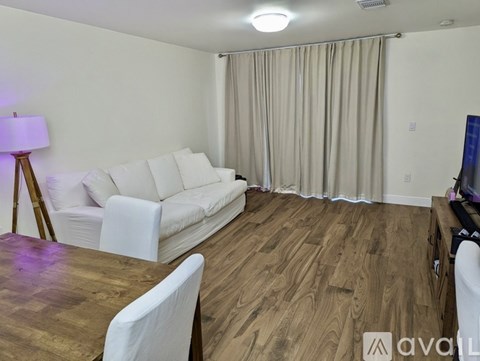 A living room with a white couch and wooden floors.