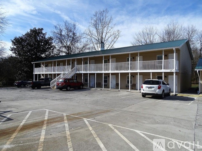 A parking lot with a building and cars parked in front.