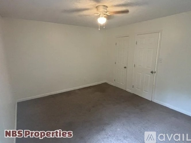 A room with a ceiling fan and two doors.