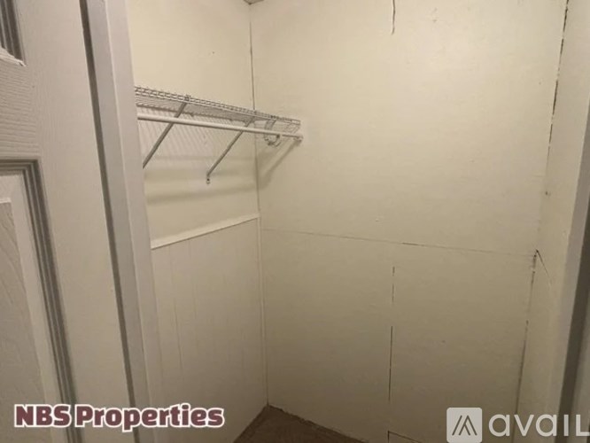 A white closet with a metal rod for hanging clothes.