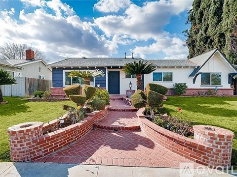 A white house with a blue door and a brick pathway leading to it.