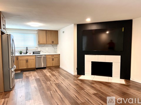 A modern kitchen with wooden floors and a black fireplace.