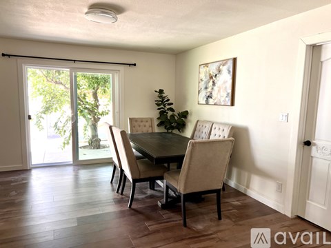 A dining room with a table and chairs and a painting on the wall.