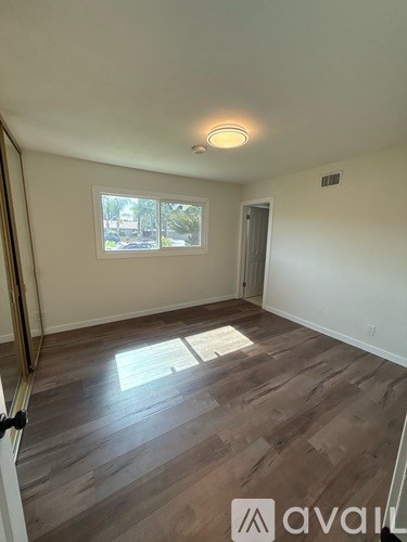A room with wooden flooring and a window letting in light.