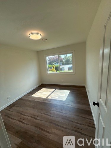 A room with wooden flooring and a window showing an outdoor view.