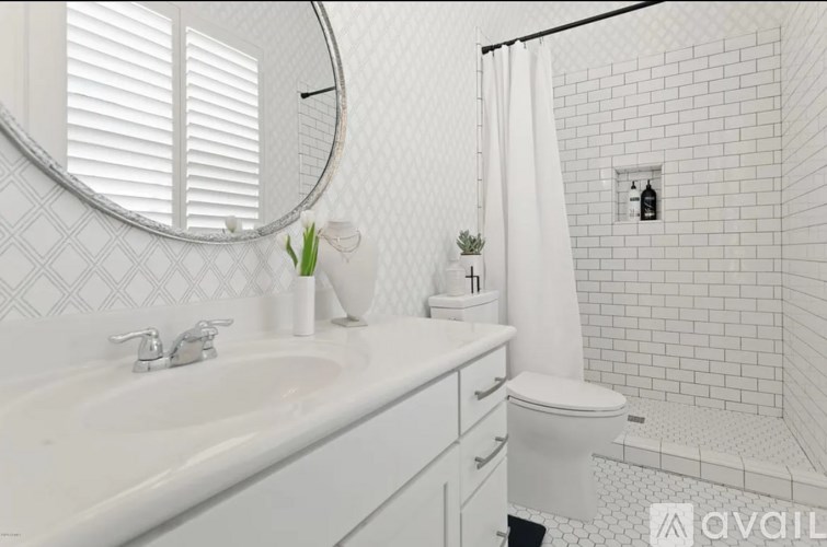 A white bathroom with a sink, toilet, and shower.