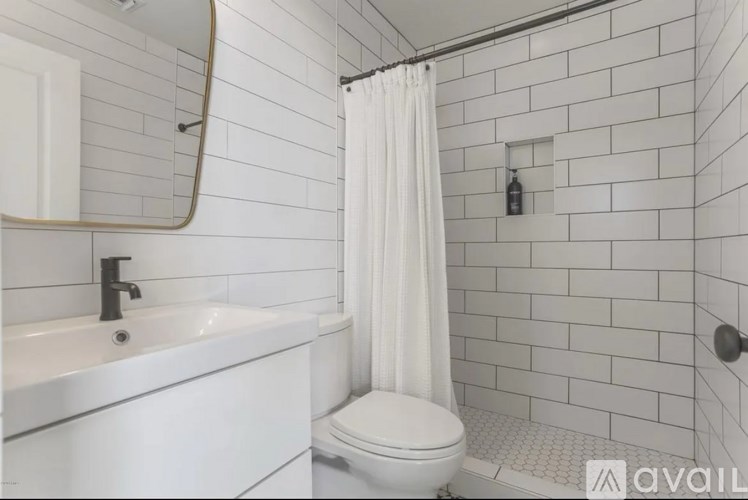 A white bathroom with a toilet, sink, and shower.